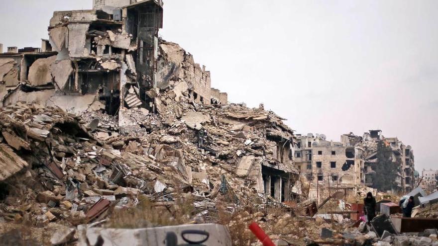 Dos personas se desplazan con sus pertenencias entre las ruinas de Alepo.