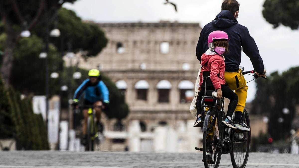 Un padre lleva a su hija en bicicleta por Roma.