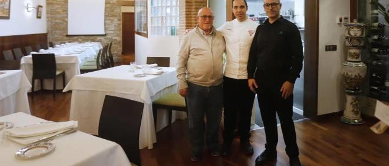 El fundador, Antonio López, con sus hijos ante el comedor y la cocina del restaurante.