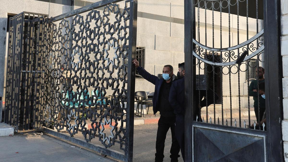 Un hombre se encuentra en una puerta mientras la gente se reúne en la frontera de Rafah, mientras se espera que los militantes de Hamás liberen a los rehenes secuestrados por Hamás durante el ataque del 7 de octubre contra Israel como parte de un acuerdo de intercambio de rehenes y prisioneros entre Hamás e Israel, como se ve desde el sur de la Franja de Gaza. 24 de noviembre de 2023.
