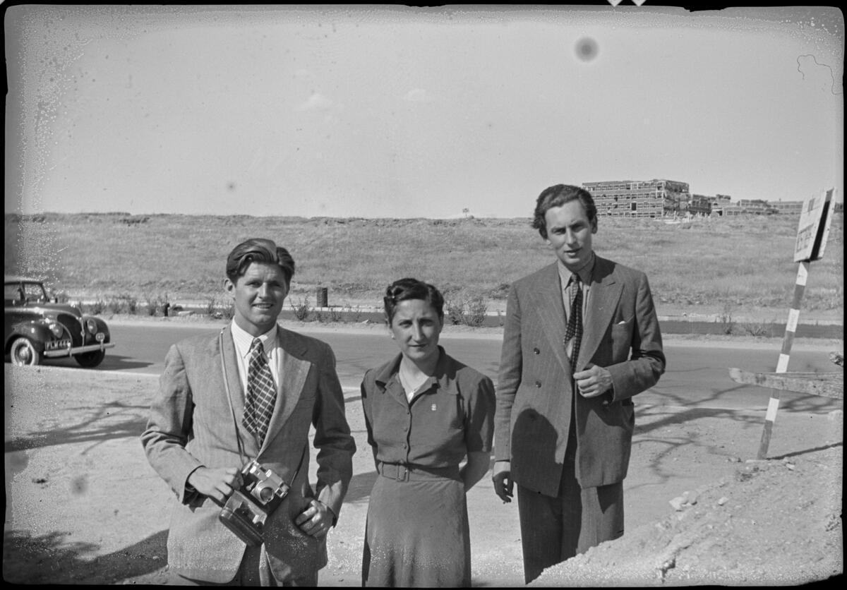 Joe volvió en el verano de 1939 a España. En la imagen posa con una cámara junto a una mujer con uniforme de la Falange y su amigo el político británico Hugh Fraser, frente a las ruinas de la Ciudad Universitaria de Madrid.