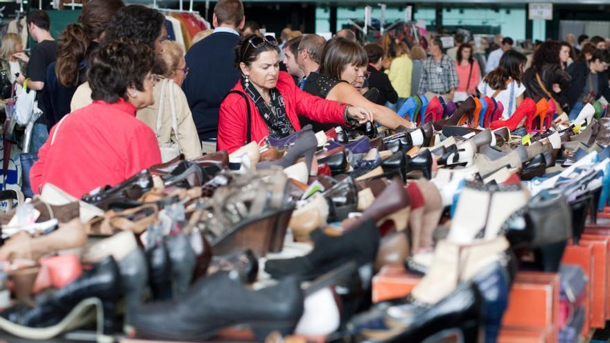 Mujeres observando un stand de calzado en la pasada feria de saldos avilesina.