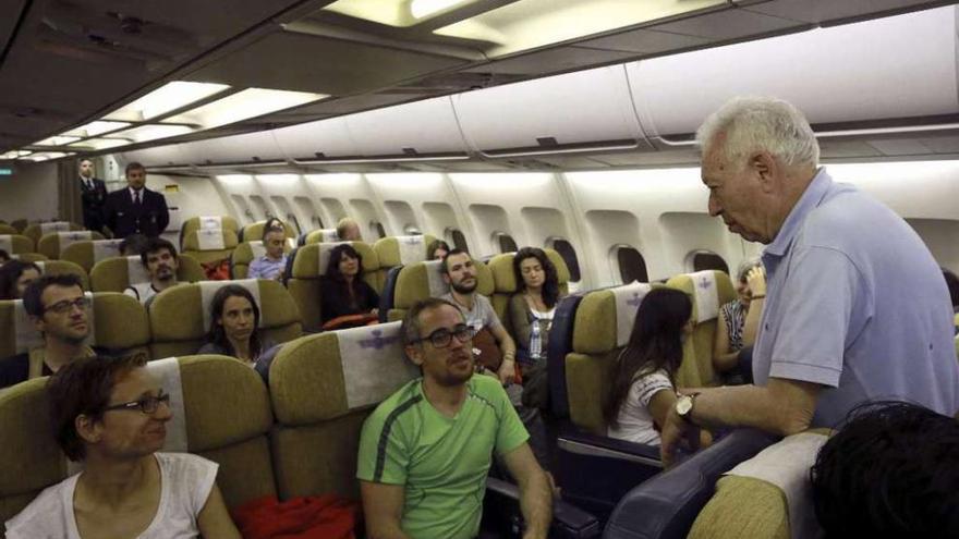 García-Margallo conversa con algunos de los turistas rescatados, ayer, en el avión de regreso a España. // Efe