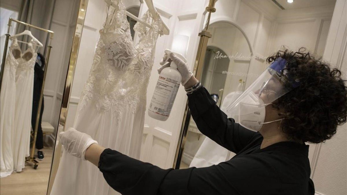 Una empleada de Pronovias, en Barcelona, desinfecta un vestido de novia