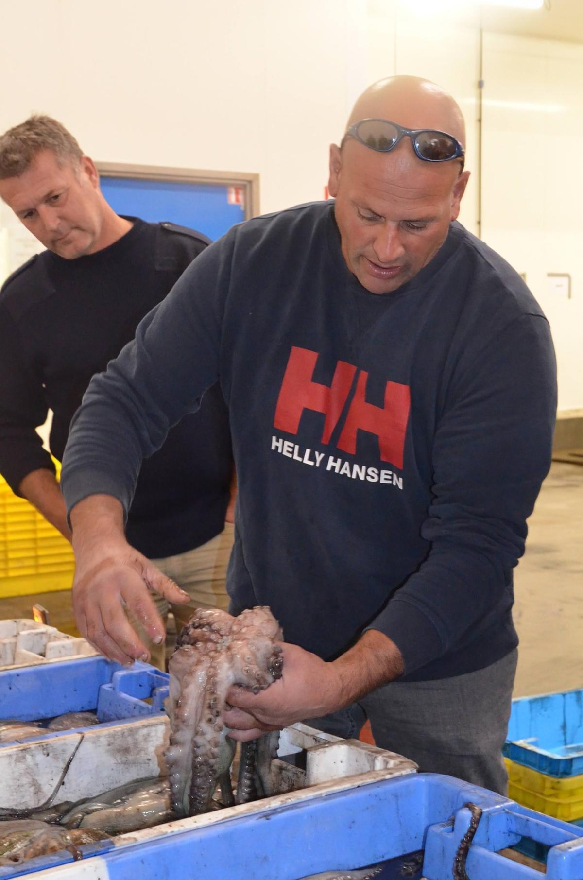 Uno de los pescadores británicos con un pulpo en la lonja