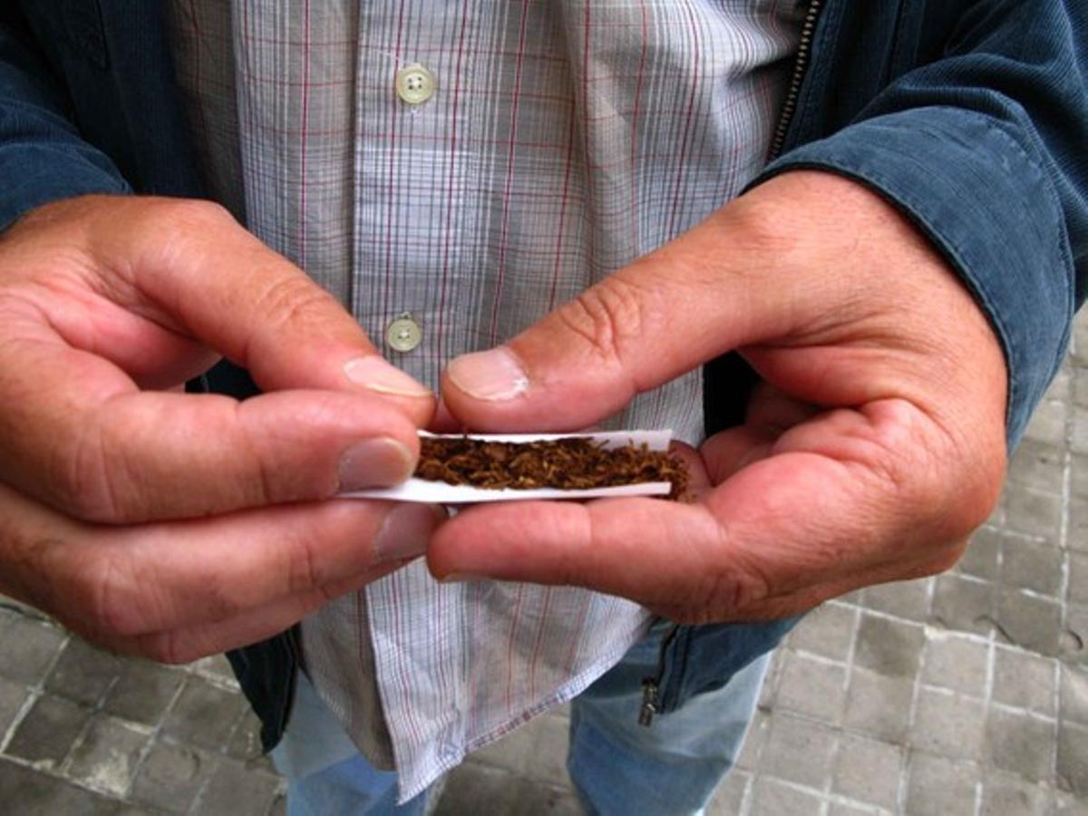 Un home es cargola un cigarret. Un home es cargola un cigarret.