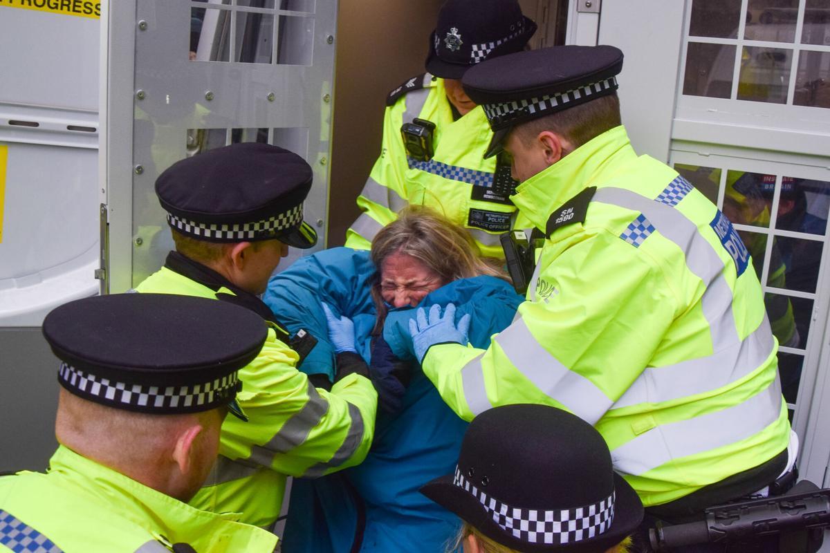 Varios policías detienen a un activista que llevaba un cartel en apoyo a Palestine Action en una protesta frente al Ministerio de Justicia británico, este jueves en Londres.