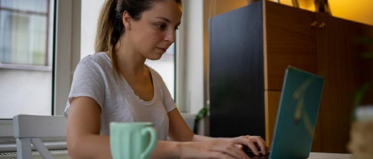 Una mujer consulta su ordenador desde su casa