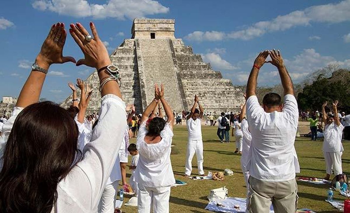 Algunes persones, dretes davant la piràmide Kukulcan a Chichén Itzá, aixequen els braços cap al sol donant la benvinguda a l’equinocci de primavera.