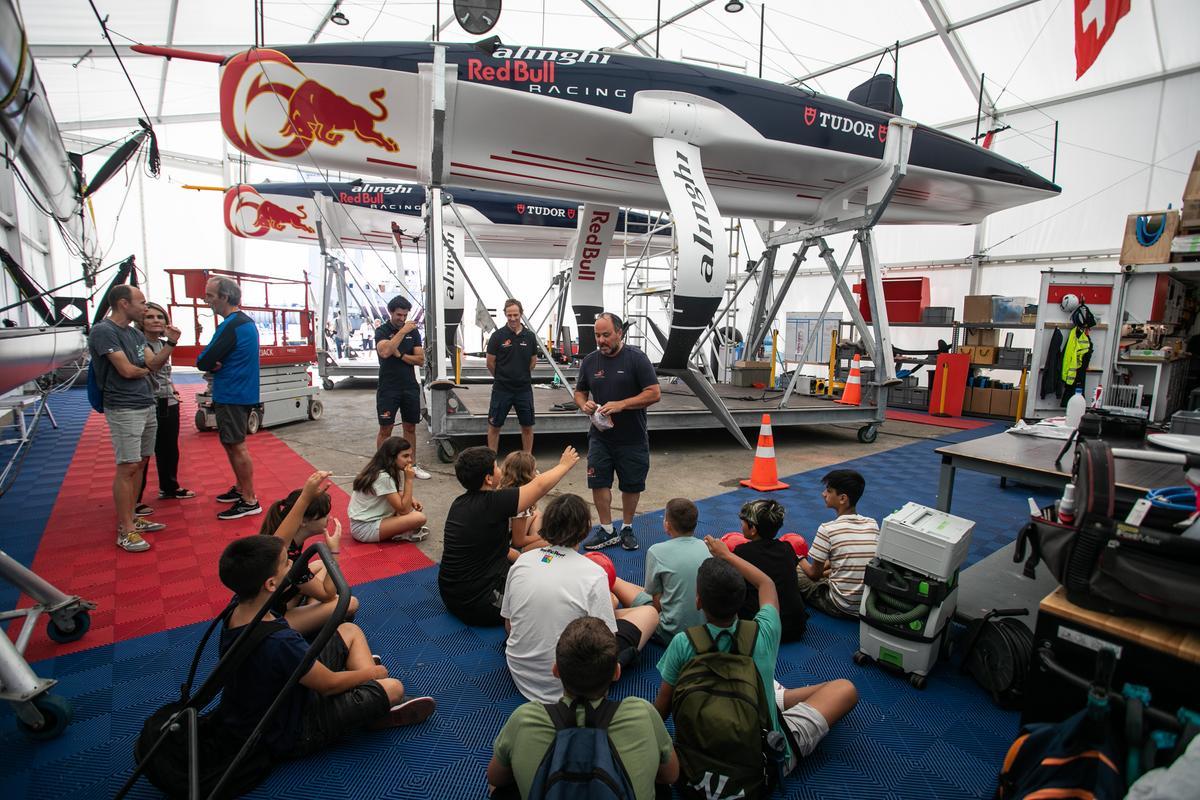 Diego Negroni, del equipo Alinghi Red Bull Racing, explica cómo funcionan las alas del monocasco AC40 a los alumnos y alumnas de la Escola Mediterrània, en el marco del proyecto 'Viu la vela' del Ayuntamiento de Barcelona.