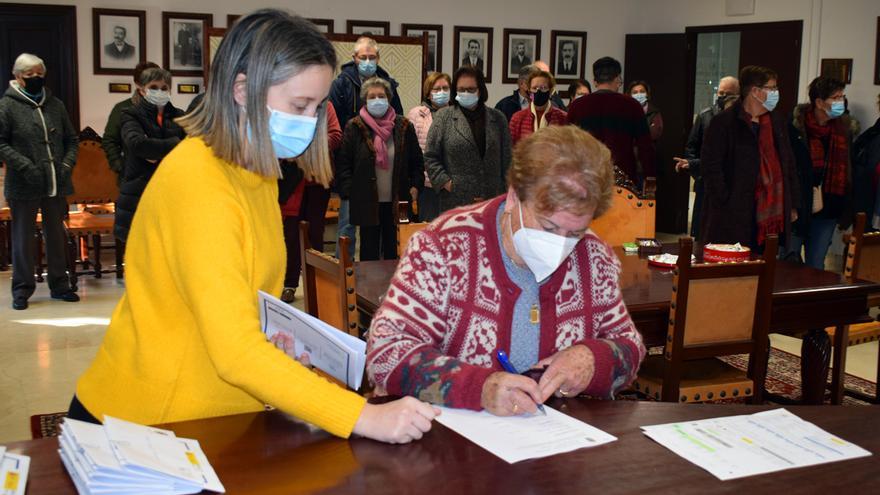 Una vecina firma los documentos.