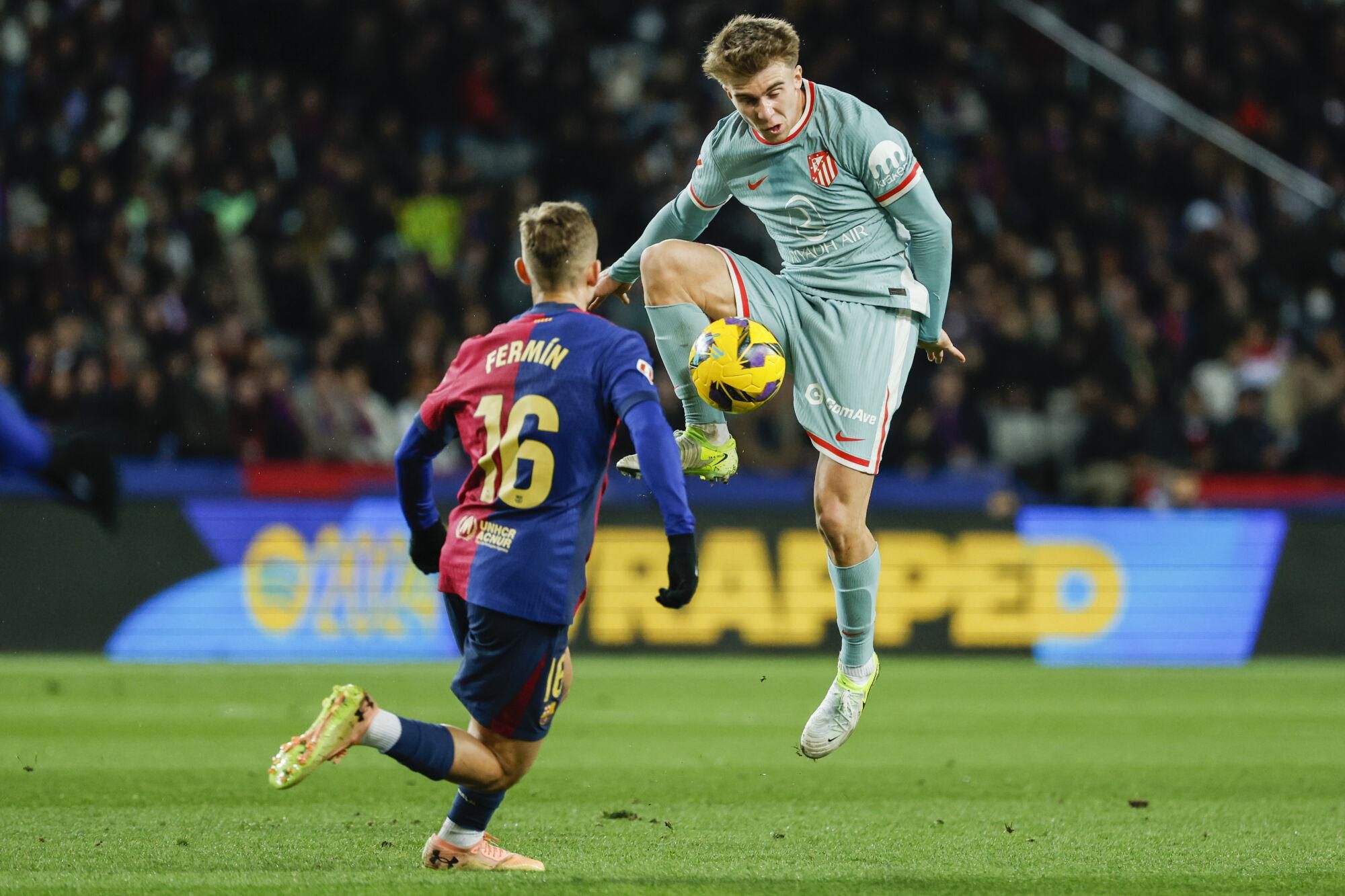 Atletico Madrid's Pablo Barrios Rivas controls the ball next to Barcelona's Fermin Lopez during the Spanish La Liga soccer match between Barcelona and Atletico Madrid at the Lluis Companys Olympic Stadium in Barcelona, Spain, Saturday, Dec. 21, 2024. (AP Photo/Joan Monfort)