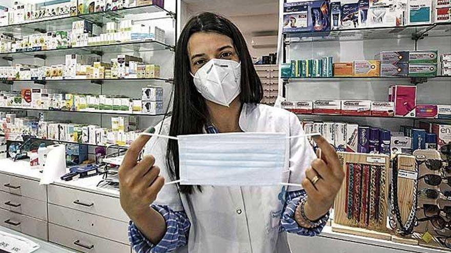 Una farmacéutica muestra una mascarilla quirúrgica