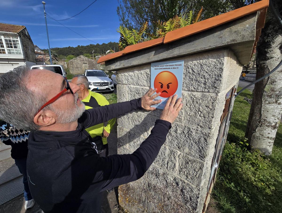 Un miembro de "Augas Limpas" coloca en la alameda de Cangas un emoticono contra la contaminación en la ría.