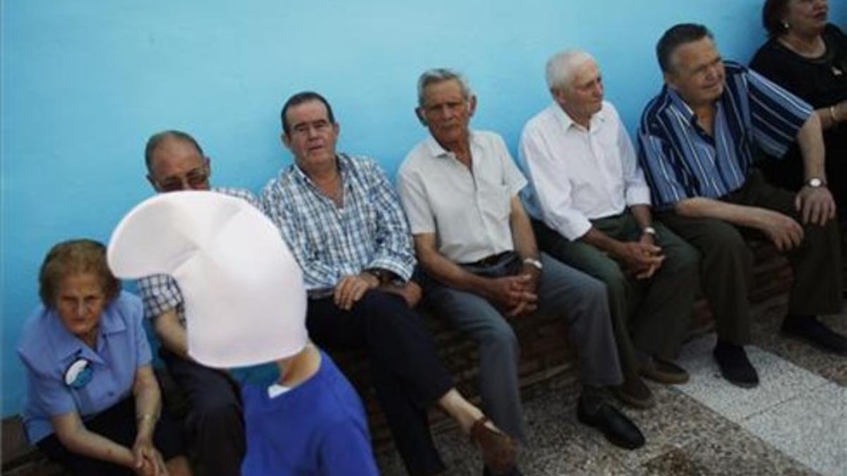 Un niño disfrazado de pitufo pasa ante unos ancianos en el pueblo malagueño.