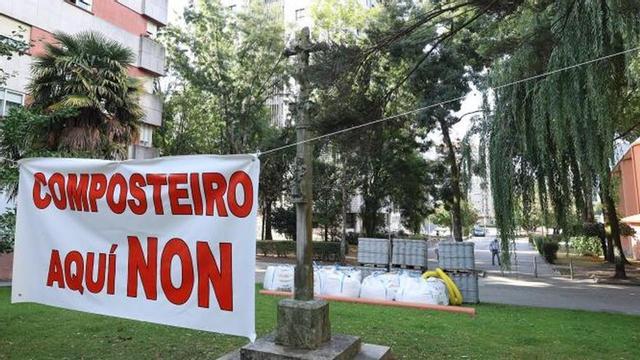 Pancarta ante el cruceiro y el material para el compostero.