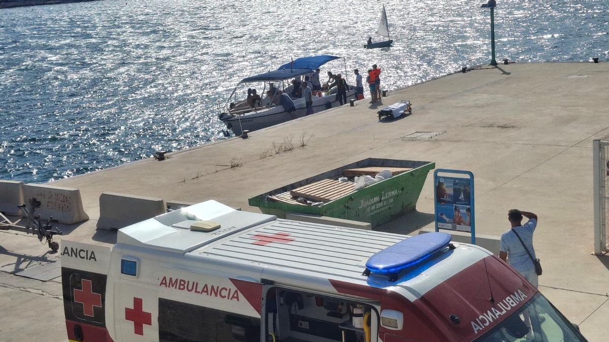 La embulancia y, al fondo, la embarcación que ha llevado a la mujer al puerto