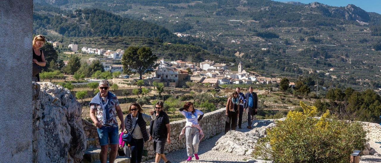 Turistas en El Castell de Guadalest, con Benimantell detrás y buena parte del valle y la sierra de Aitana al fondo, en una imagen reciente.