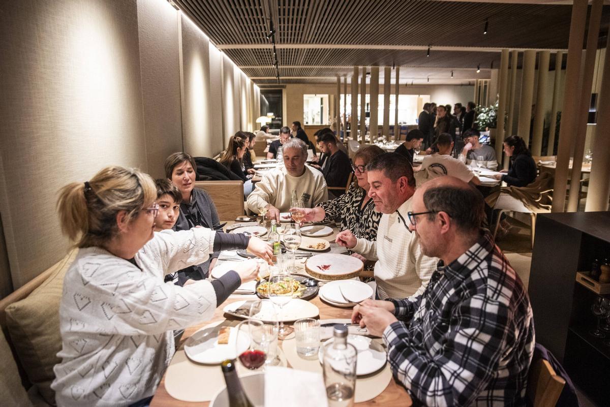 Mesas llenas en el restaurante Divers, en Manresa (Barcelona), donde, en primer plano, una familia que comparte platos.