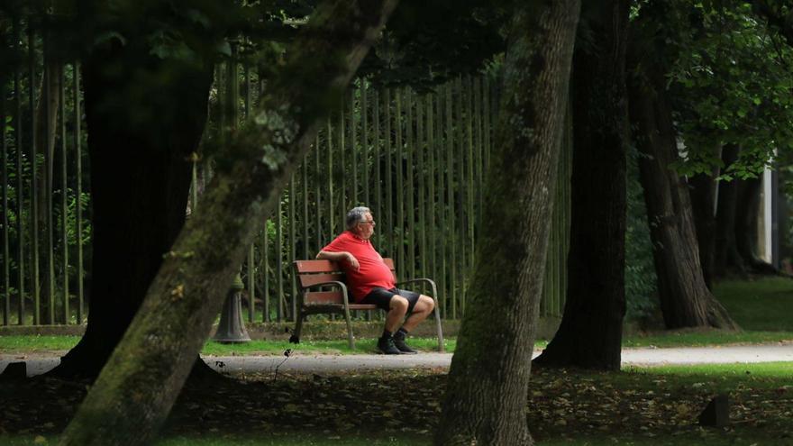 Un hombre descansa en un banco del parque Ferrera de Avilés.