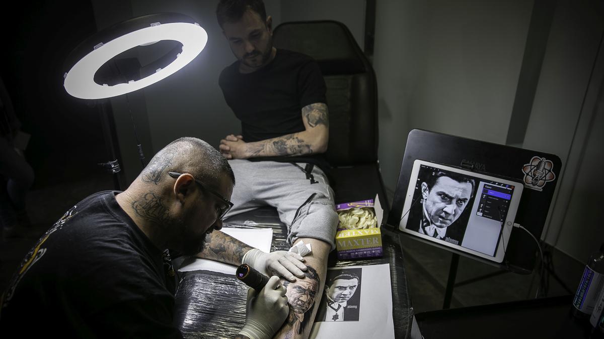 Artista tatuador profesional haciendo tatuaje en el brazo de un