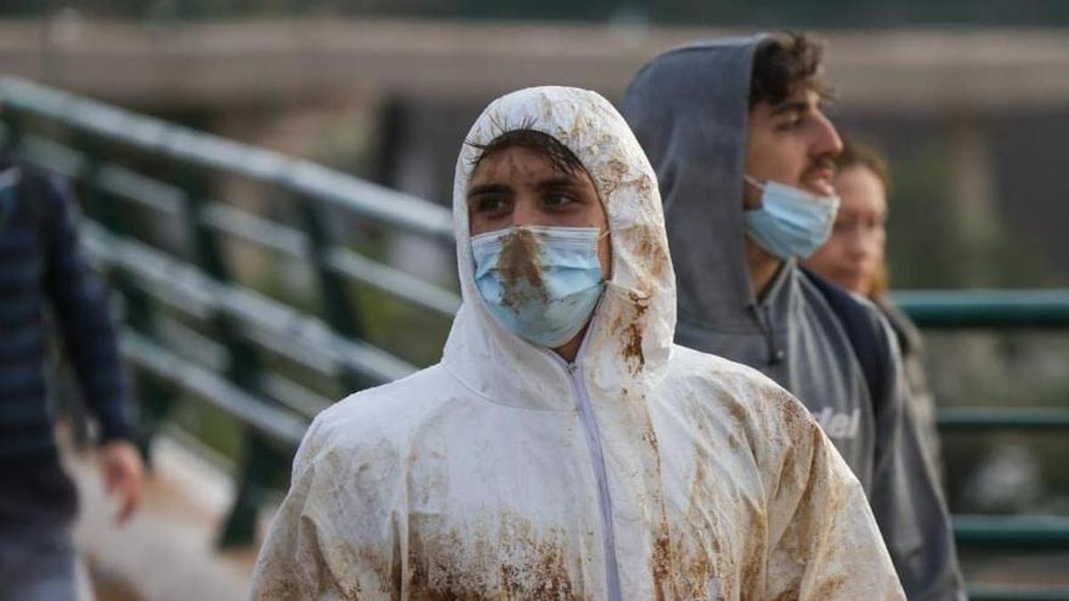 Voluntarios con monos y mascarillas en la zona de la riada. / F. Calabuig