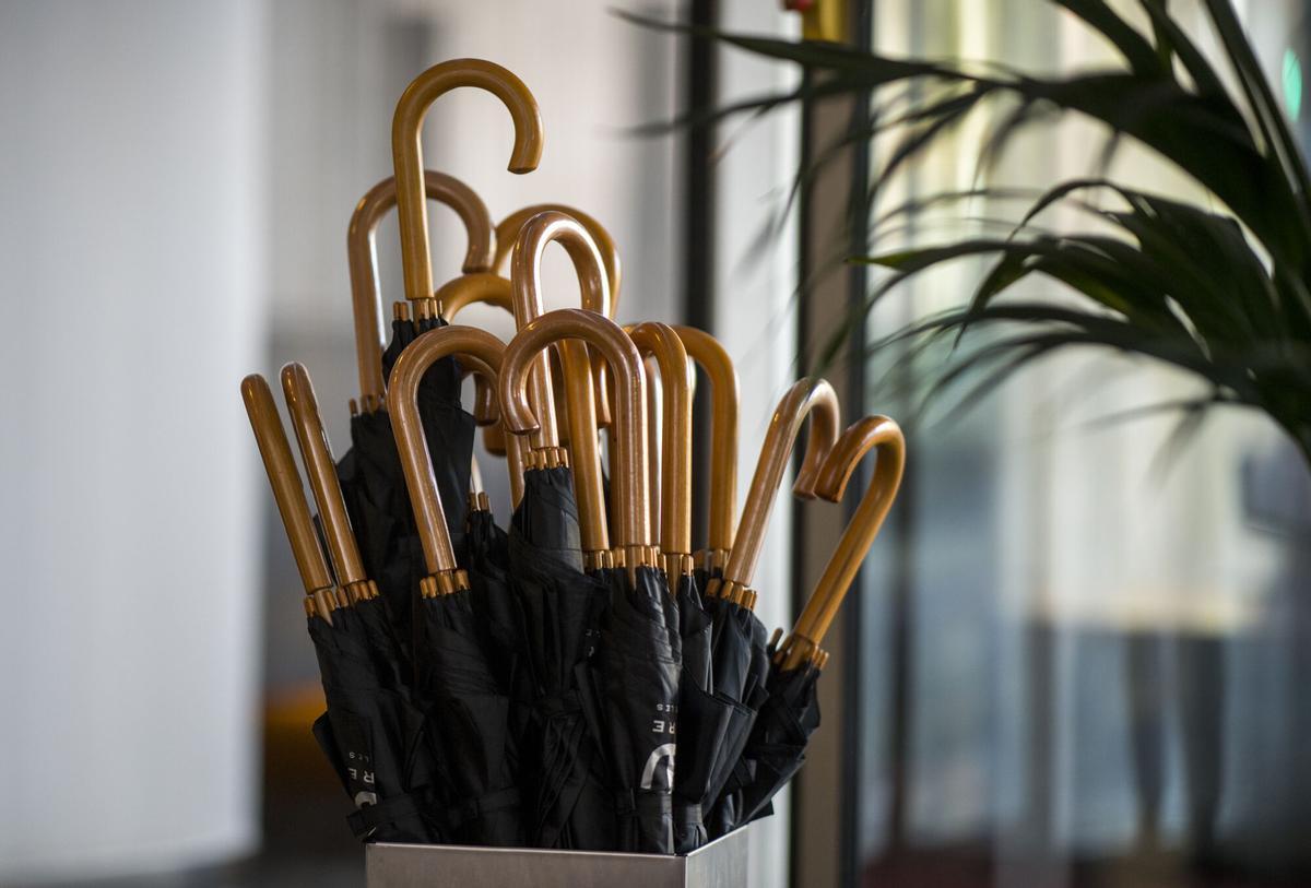 Un paragüero lleno de paraguas negros.