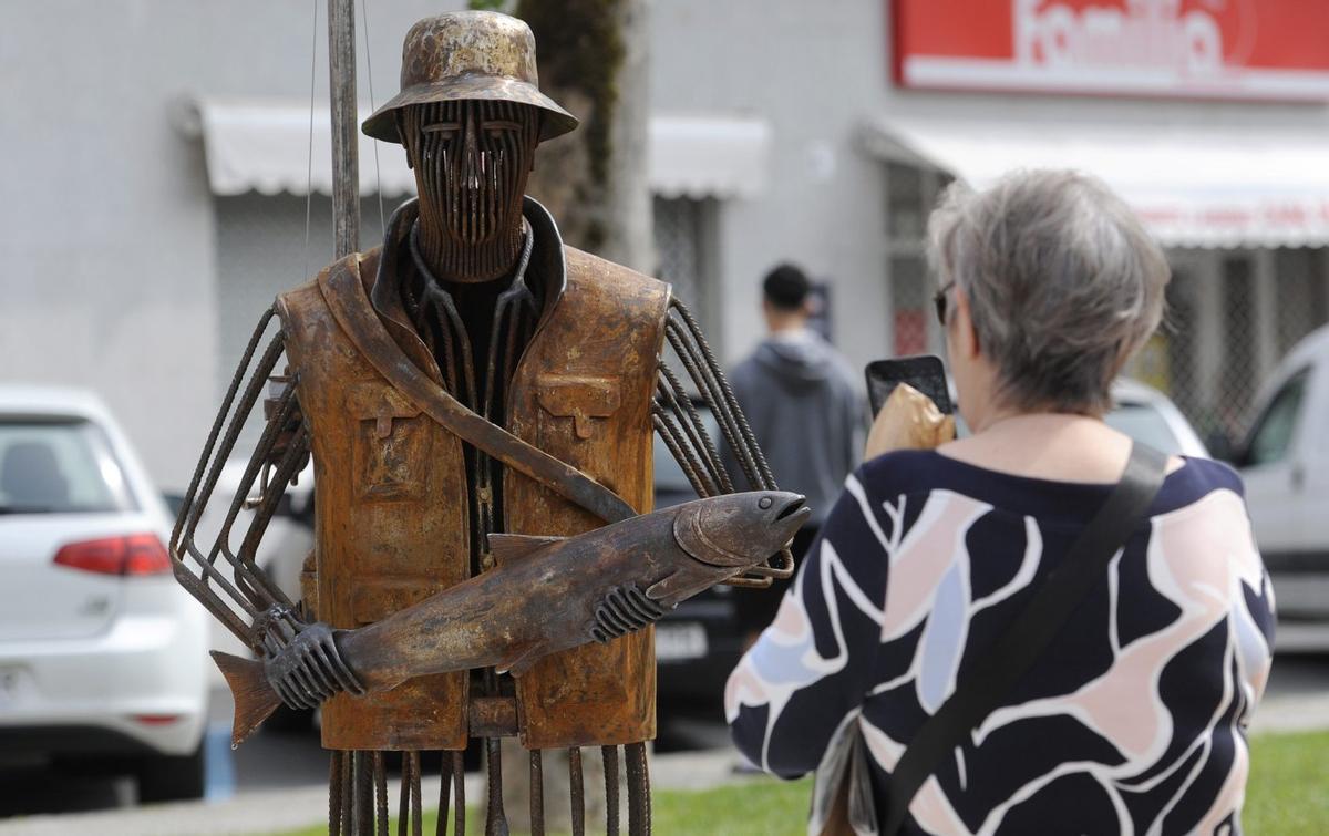 Una vecina saca una foto al pescador tras aparecer por sorpresa en la Festa do Salmón del 2025. | BERNABÉ/JAVIER LALÍN