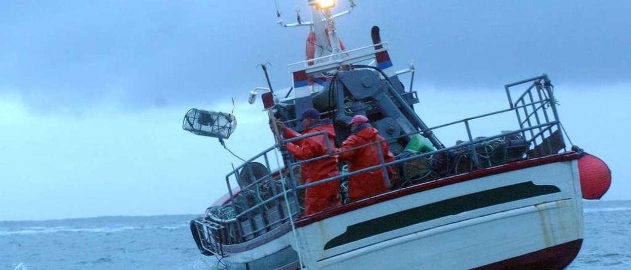 Dos marineros en un barco de madera cargado de nasas en la ría de Arousa. // Iñaki Abella