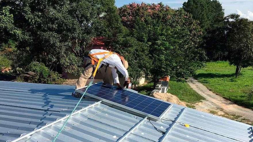 Un hombre instala una placa solar en un tejado.