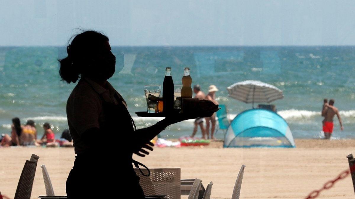 Una camarera lleva bandeja con bebidas en un restaurante.