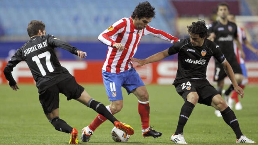 El centrocampista turco del Atlético de Madrid, Arda Turan (c), controla el balón entre el argentino Tino Costa (d) y Jordi Alba, del Valencia CF