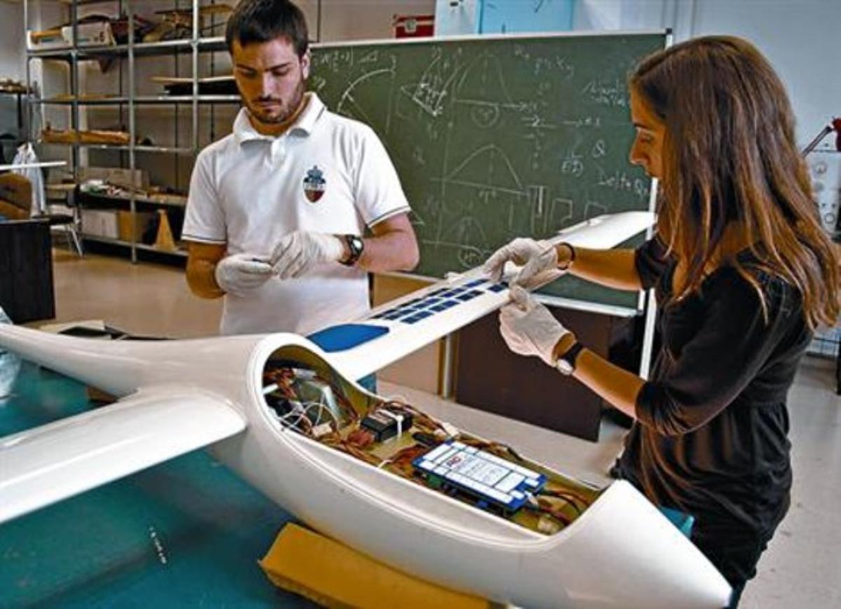 Dos estudiants de la UPC treballen en la instal·lació dels panells solars del petit prototip.