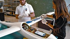 Dos estudiantes de la UPC trabajan en la instalación de los paneles solares del pequeño prototipo.