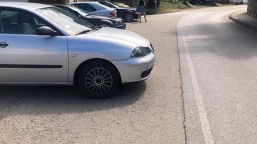 Coches aparcados casi en el centro de la carretera en Caso.