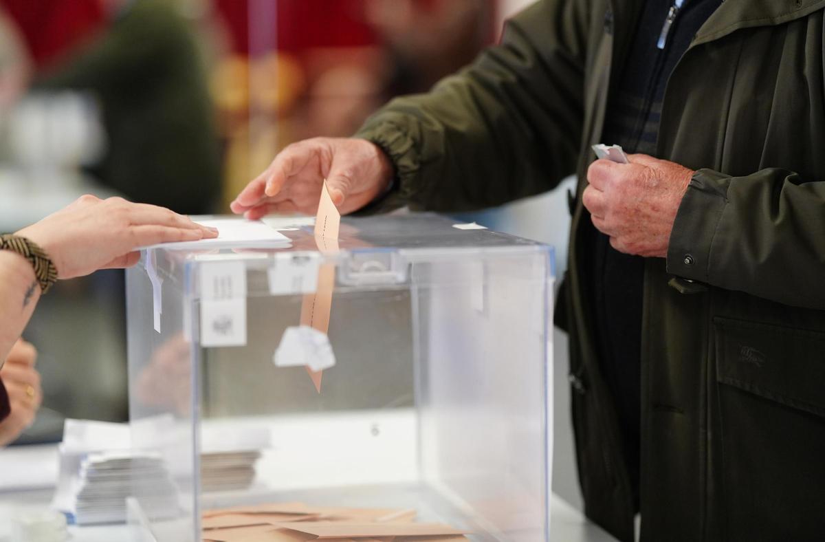 Un hombre deposita su voto en la urna.