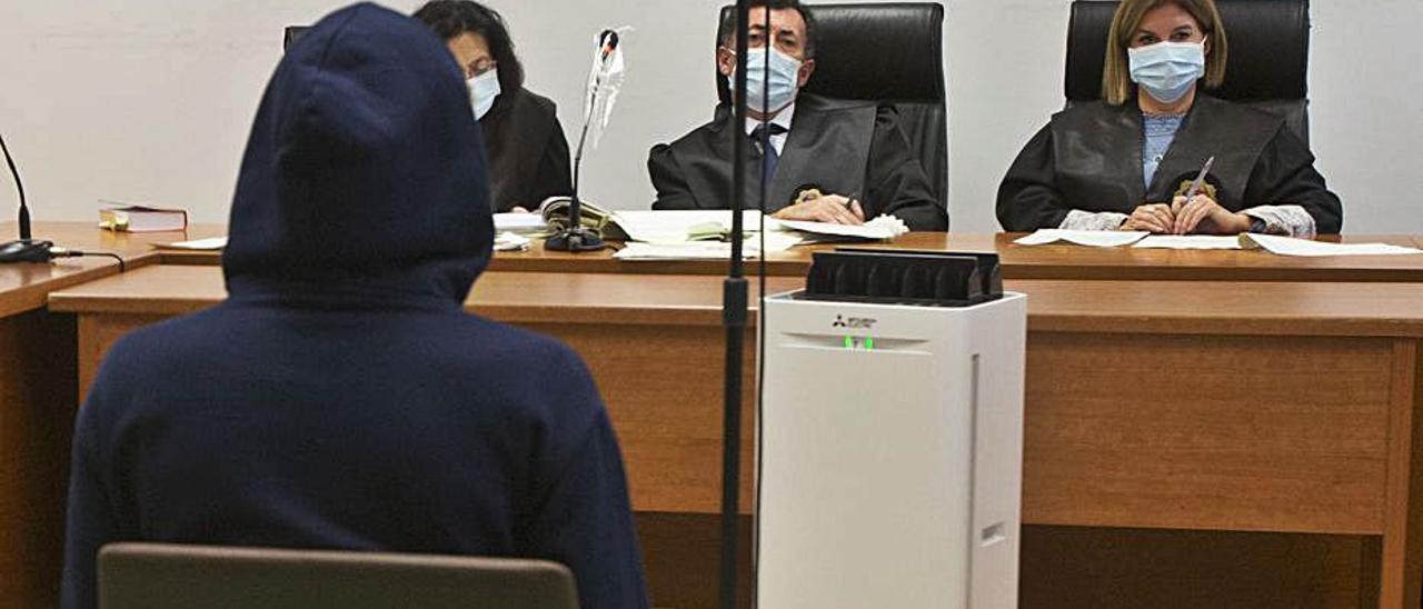 El acusado se tapa la cabeza con una capucha en el juicio.