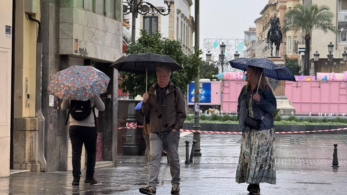 Personas en la plaza de las Tendillas, hoy, bajo la lluvia.