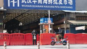 Archivo - Dos ciudadanos pasan por la entrada del mercado de mariscos Huanan en Wuhan, provincia de Hubei, en el centro de China, el 29 de enero.