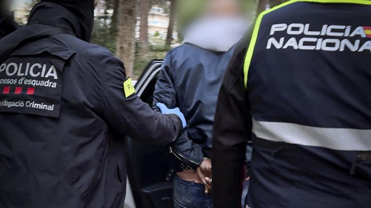 Agentes de los Mossos d'Esquadra y la Policía Nacional trasladan a uno de los detenidos por pertenecer a la banda de los Trinitarios.