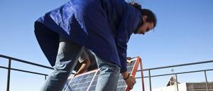 Un hombre instala placas fotovoltaicas en la cubierta de un edificio.