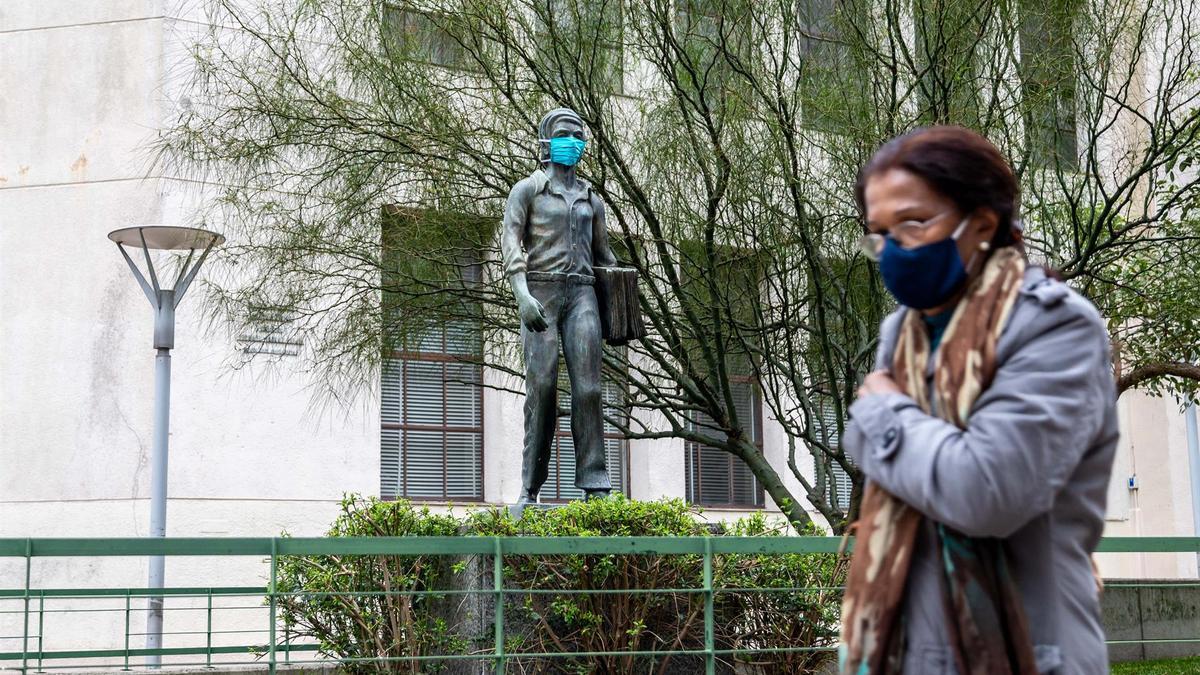 Una mujer pasa frente a una estatua con mascarilla en Montevideo, acción promovida por el Gobierno para fomentar el uso de mascarilla.