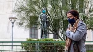 Una mujer pasa frente a una estatua con mascarilla en Montevideo, acción promovida por el Gobierno para fomentar el uso de mascarilla.