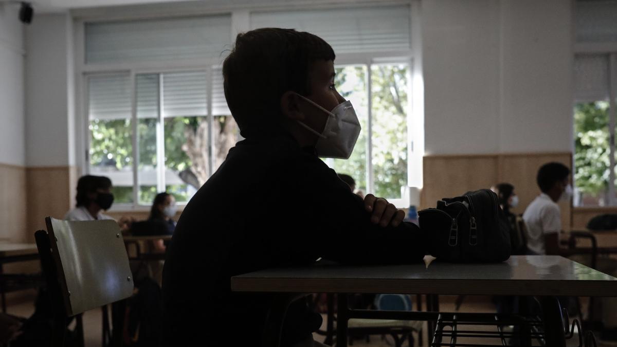 Un niño con mascarilla en un aula de un colegio.