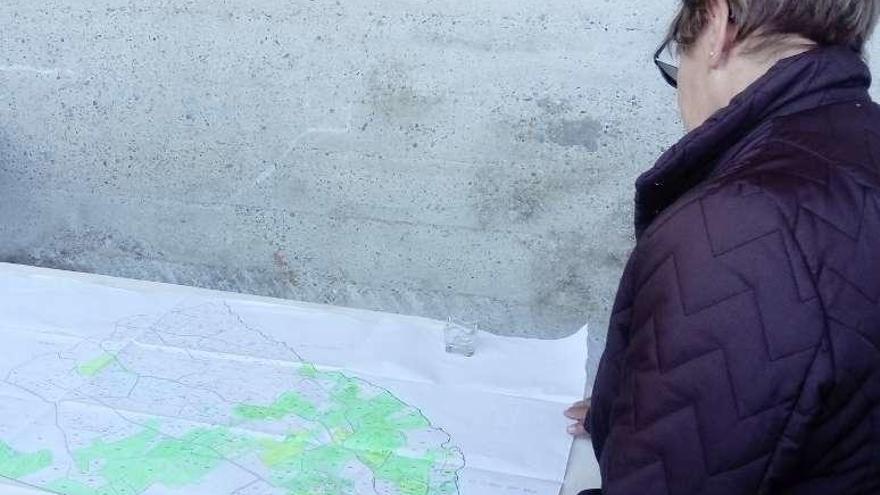 Una vecina examina el mapa de la concentración, donde se ve la mancha verde de las fincas que quieren ser excluidas.