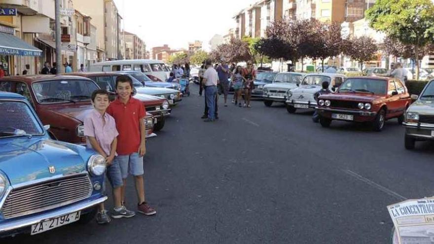 Dos niños y varias personas, en la concentración de coches clásicos.