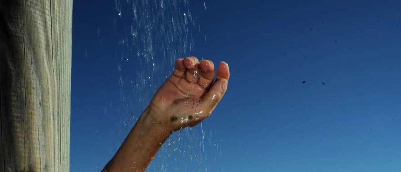 Un bañista en una de las duchas de la playa Compostela, en imagen de archivo. // Iñaki Abella