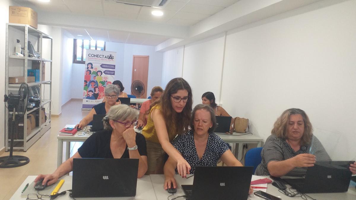 La monitora del curso enseña a las participantes elementos del ordenador.