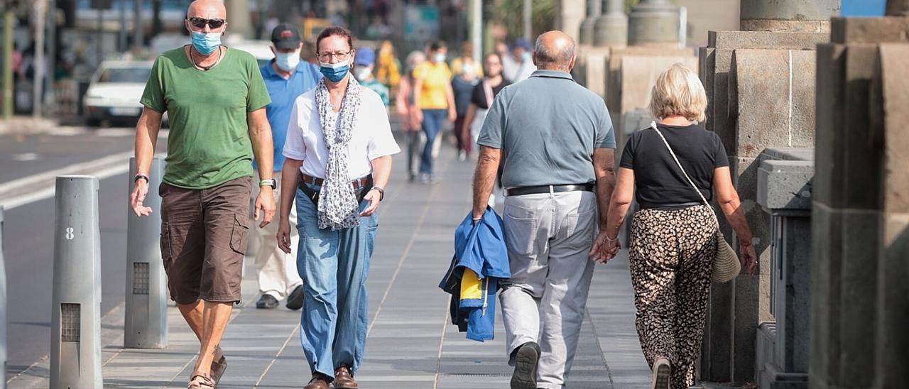 Varias personas pasean en Santa Cruz de Tenerife con mascarilla para evitar el coronavirus.