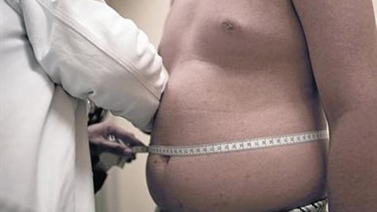 Un médico mide el perímetro abdominal de un hombre que sufre obesidad.
